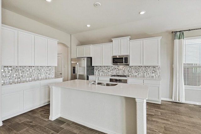 kitchen featuring a kitchen island with sink, white cabinets, sink, decorative backsplash, and stainless steel appliances