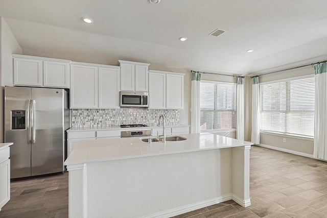 kitchen featuring sink, tasteful backsplash, a center island with sink, white cabinets, and appliances with stainless steel finishes