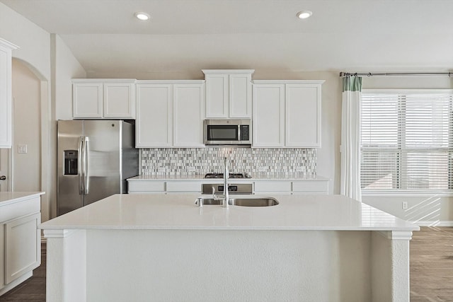 kitchen featuring backsplash, white cabinetry, an island with sink, and stainless steel appliances