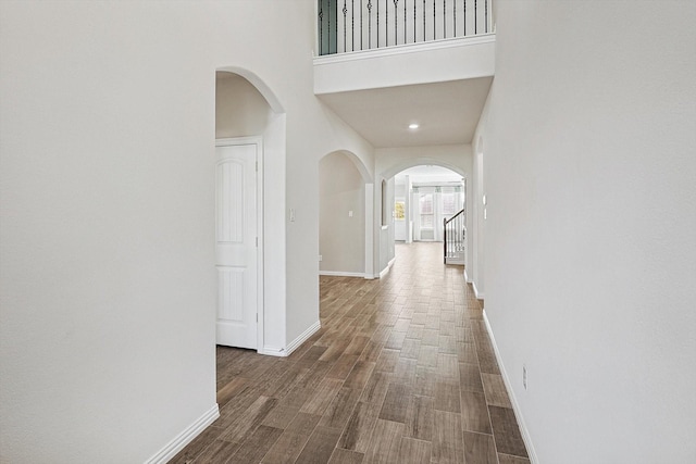 hallway with dark hardwood / wood-style floors and a high ceiling