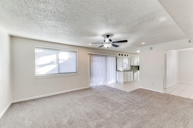 unfurnished living room featuring ceiling fan, sink, and light colored carpet