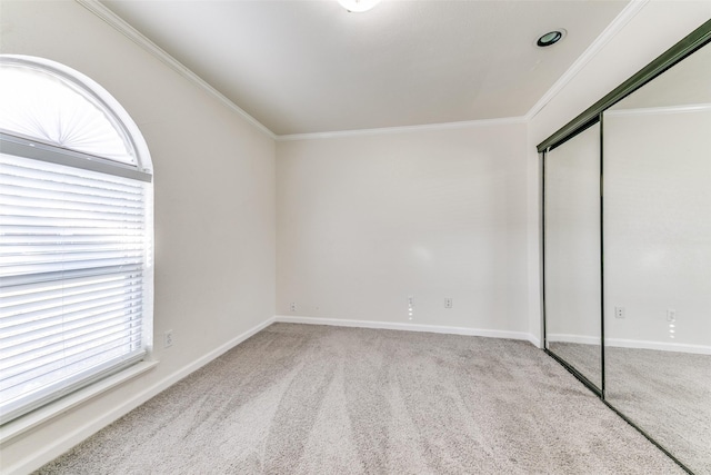 unfurnished bedroom with light colored carpet, crown molding, and a closet