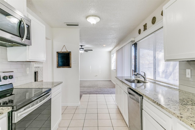 kitchen with white cabinets, sink, light colored carpet, and stainless steel appliances