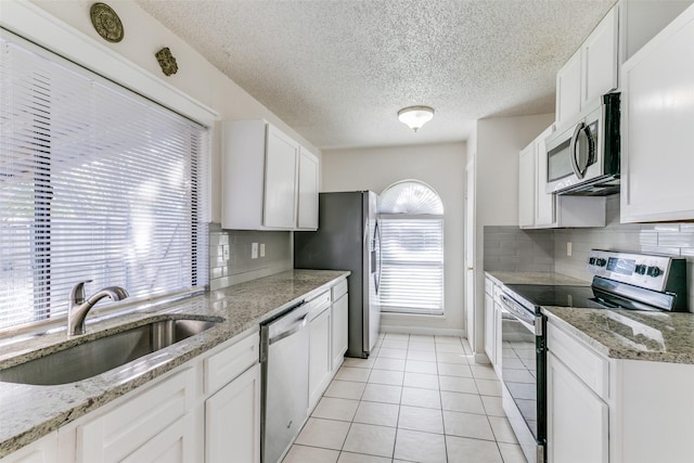 1629 Shreveport Trl, Plano, TX 75023 - kitchen featuring appliances with stainless steel finishes, a sink, decorative backsplash, white cabinetry, and a textured ceiling