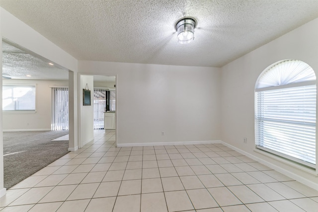 1629 Shreveport Trl, Plano, TX 75023 - spare room featuring a textured ceiling, baseboards, light colored carpet, and light tile patterned floors