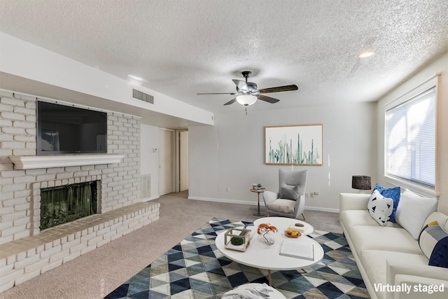 living room featuring ceiling fan, light colored carpet, a textured ceiling, and a brick fireplace