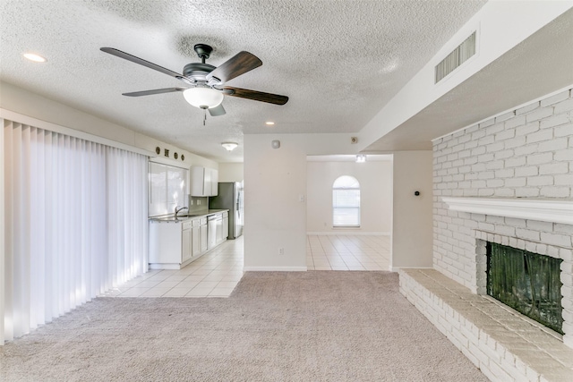 1629 Shreveport Trl, Plano, TX 75023 - unfurnished living room featuring light carpet, light tile patterned floors, a ceiling fan, a textured ceiling, and a fireplace