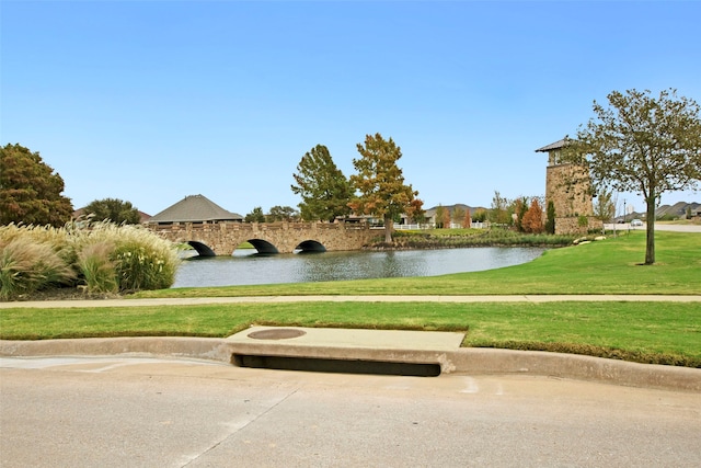 view of home's community with a water view and a yard