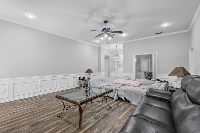 living room featuring a textured ceiling, ceiling fan, ornamental molding, and dark wood-type flooring