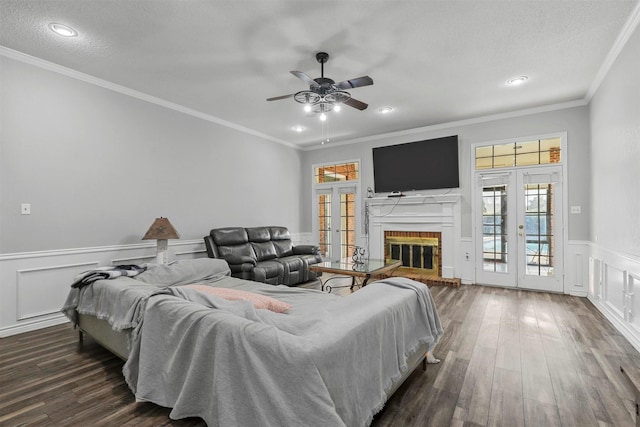 living room with a brick fireplace, dark wood-type flooring, crown molding, and french doors