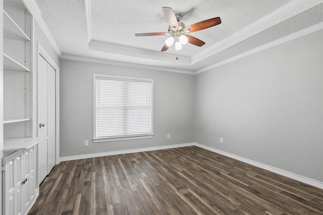 unfurnished room with ceiling fan, dark wood-type flooring, a raised ceiling, crown molding, and a textured ceiling