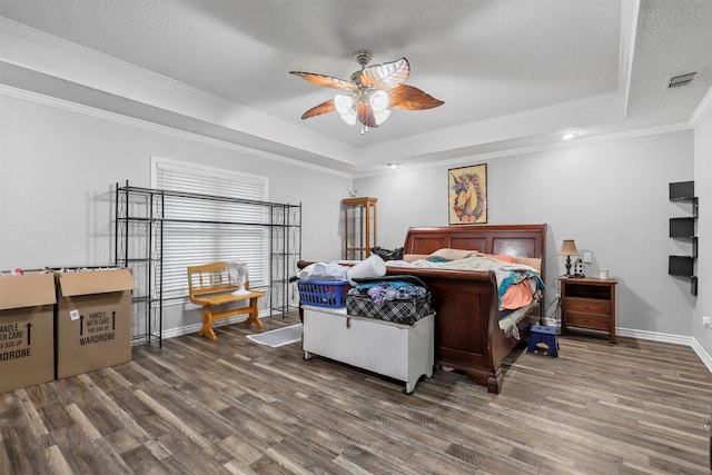 bedroom featuring ornamental molding, a textured ceiling, a raised ceiling, ceiling fan, and hardwood / wood-style flooring