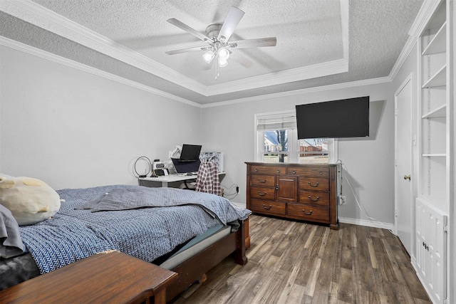 bedroom featuring dark wood-type flooring, a raised ceiling, ceiling fan, ornamental molding, and a textured ceiling