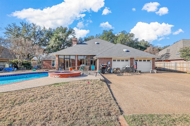 back of property with a patio, a garage, and a pool with hot tub