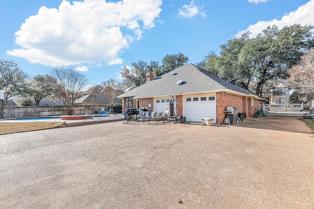 view of front of home with a garage and a covered pool