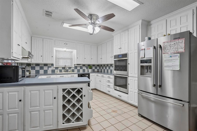 kitchen featuring white cabinets, ceiling fan, light tile patterned floors, a textured ceiling, and stainless steel appliances