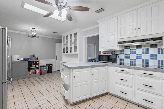 kitchen featuring crown molding, white cabinetry, light tile patterned flooring, kitchen peninsula, and stainless steel refrigerator