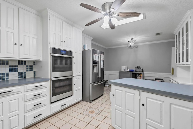 kitchen with appliances with stainless steel finishes, white cabinets, ornamental molding, light tile patterned floors, and ceiling fan