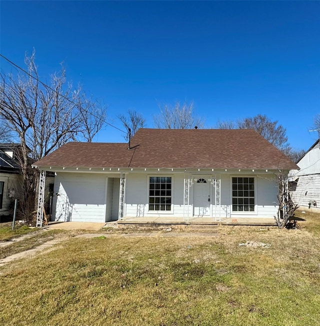 ranch-style home with covered porch, a front lawn, and a shingled roof