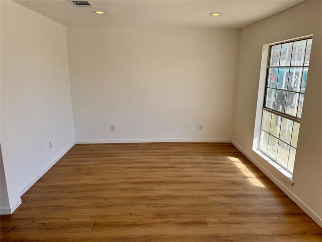 unfurnished room featuring visible vents, baseboards, wood finished floors, and recessed lighting