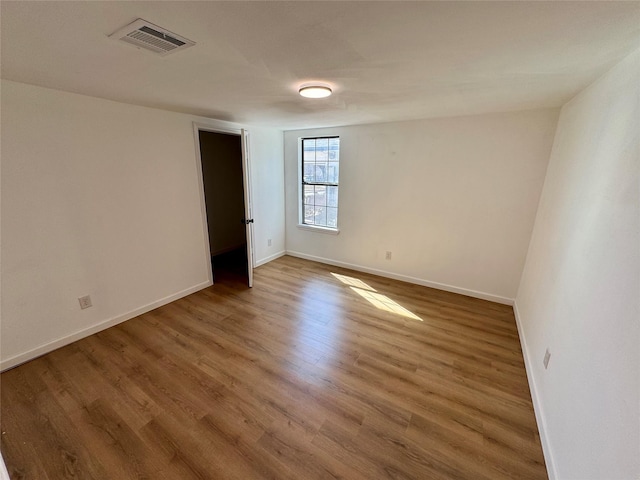 unfurnished room with baseboards, visible vents, and wood finished floors