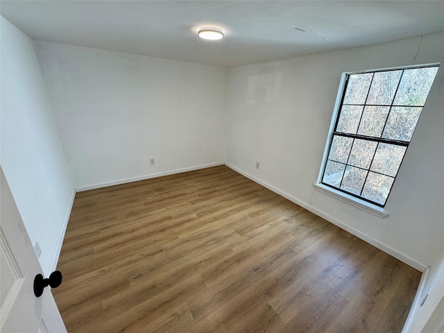 unfurnished room with baseboards and wood finished floors