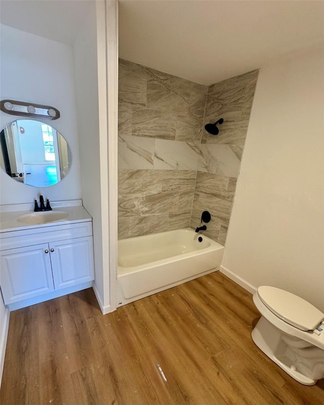 full bath featuring toilet, wood finished floors, vanity, bathing tub / shower combination, and baseboards