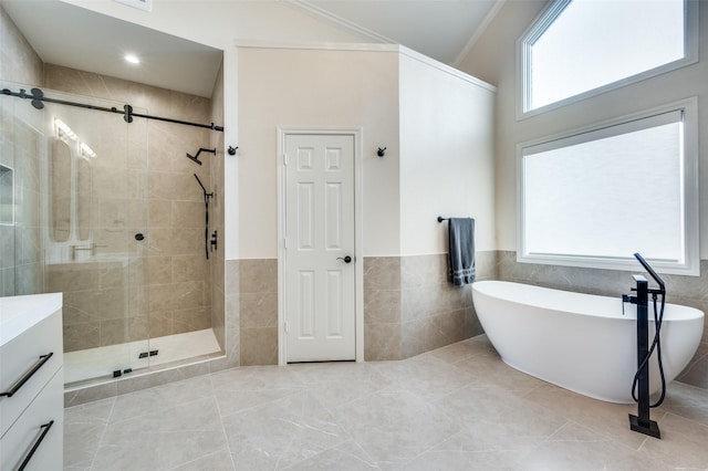 full bathroom featuring a wainscoted wall, tile walls, a freestanding bath, a shower stall, and tile patterned floors