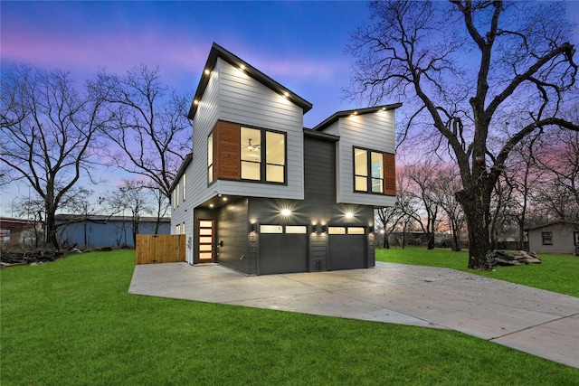 back house at dusk with a lawn and a garage