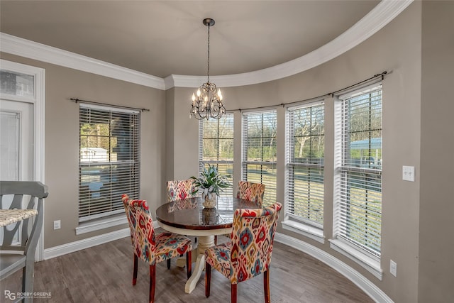 dining space with ornamental molding, hardwood / wood-style floors, and a chandelier