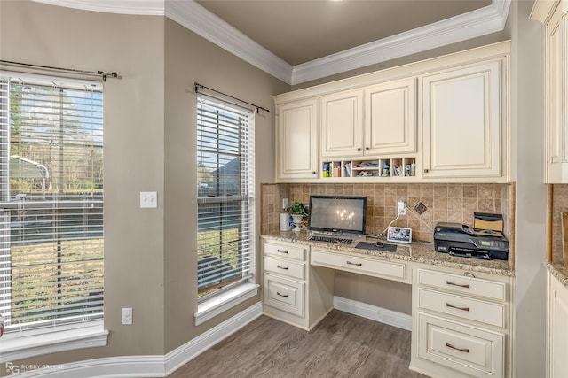 home office with ornamental molding, built in desk, and light hardwood / wood-style flooring