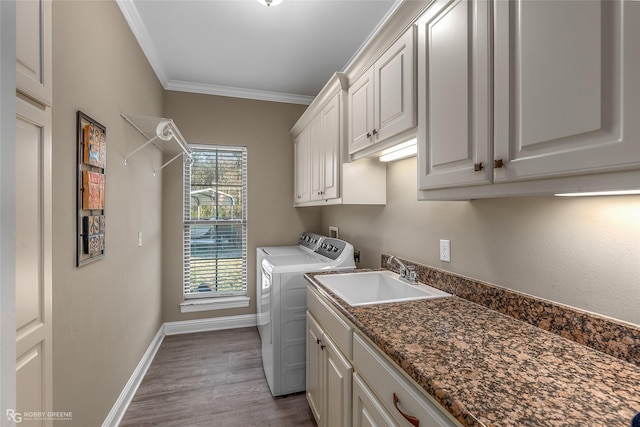 laundry room with sink, crown molding, cabinets, wood-type flooring, and washer and dryer