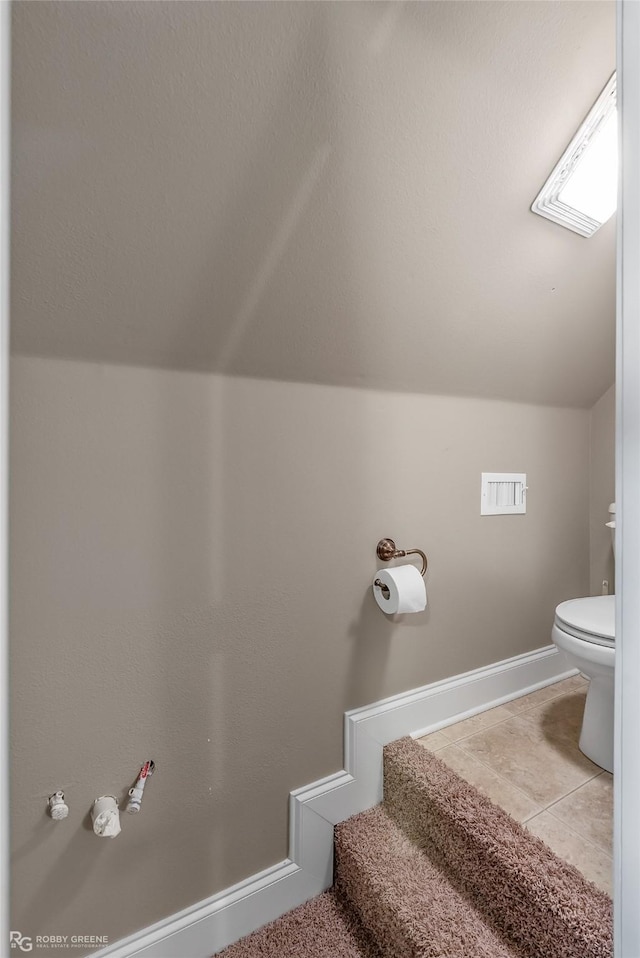 bathroom with lofted ceiling, tile patterned flooring, and toilet