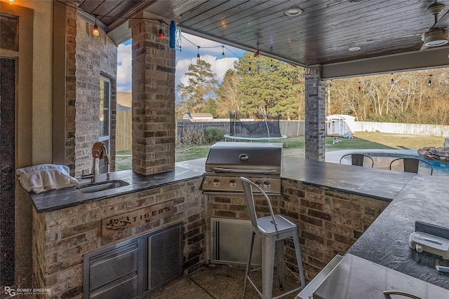 view of patio with a grill, sink, and a trampoline