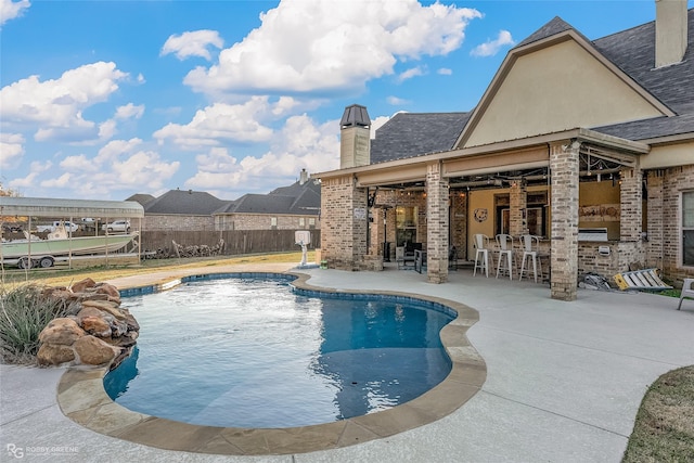 view of pool with a bar and a patio