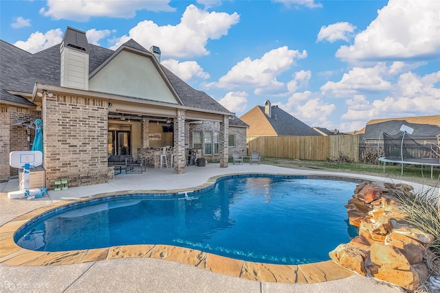 view of pool with a trampoline, a patio area, and an outdoor bar