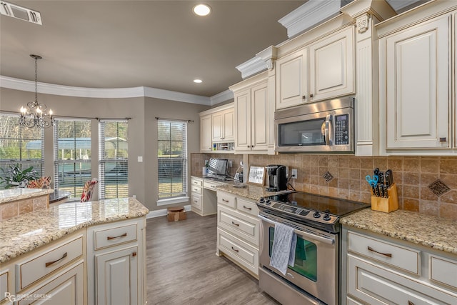 kitchen with decorative backsplash, hanging light fixtures, stainless steel appliances, crown molding, and cream cabinetry