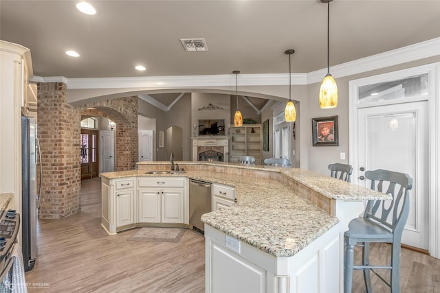 kitchen with sink, light hardwood / wood-style flooring, a breakfast bar, light stone counters, and decorative light fixtures