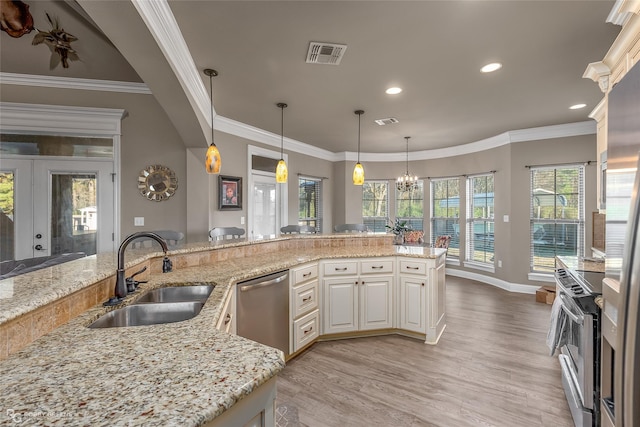 kitchen with light stone counters, sink, decorative light fixtures, and appliances with stainless steel finishes