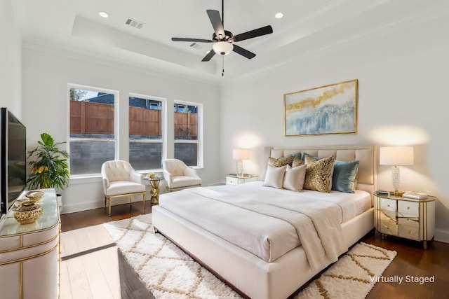 bedroom featuring dark hardwood / wood-style flooring, a raised ceiling, ceiling fan, and crown molding