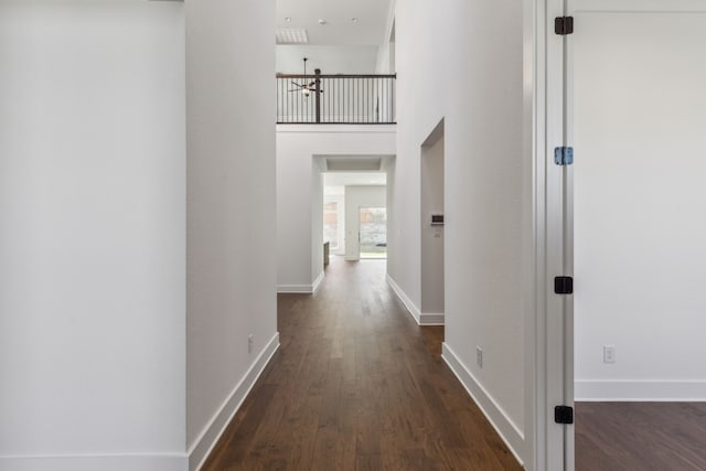 hall featuring a towering ceiling and dark hardwood / wood-style floors