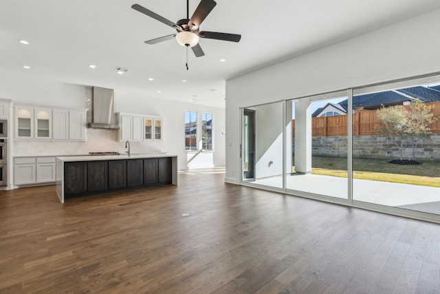 unfurnished living room with ceiling fan, dark wood-type flooring, and sink