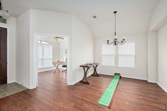 workout area featuring ceiling fan with notable chandelier, dark hardwood / wood-style floors, vaulted ceiling, and a healthy amount of sunlight