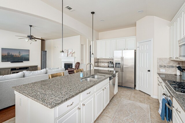 kitchen with sink, hanging light fixtures, a kitchen island with sink, white cabinets, and appliances with stainless steel finishes