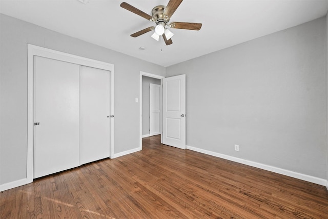 unfurnished bedroom with dark wood-type flooring, ceiling fan, and a closet