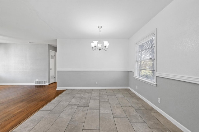 spare room with an inviting chandelier and hardwood / wood-style flooring