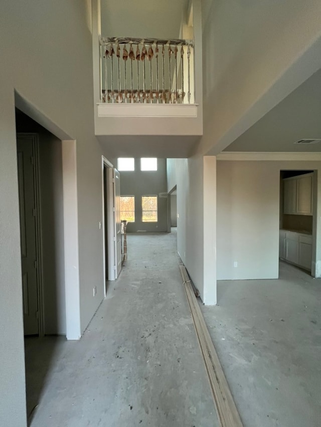 corridor featuring a high ceiling, visible vents, and crown molding