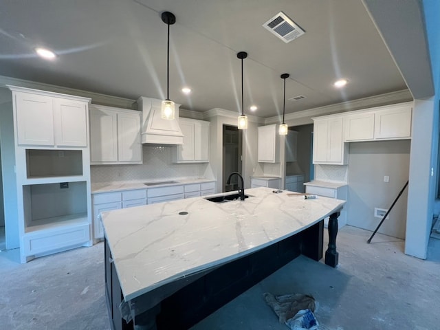 kitchen with visible vents, decorative backsplash, a large island with sink, premium range hood, and a sink