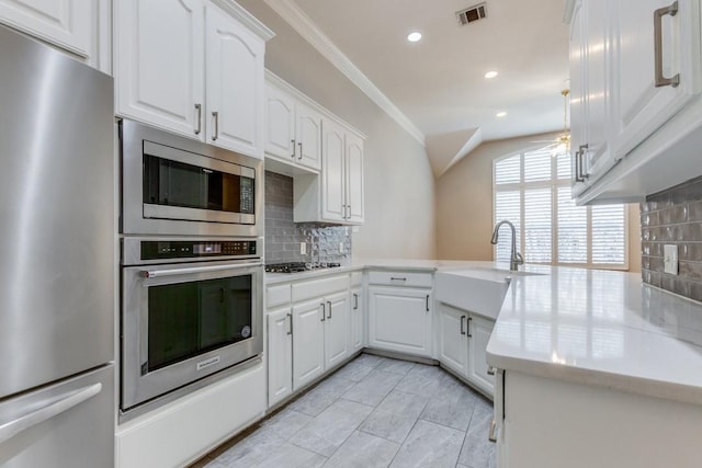 kitchen featuring white cabinets, decorative backsplash, kitchen peninsula, and appliances with stainless steel finishes