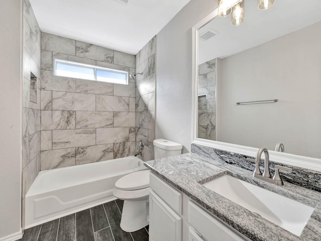 full bathroom featuring vanity, tiled shower / bath combo, and toilet